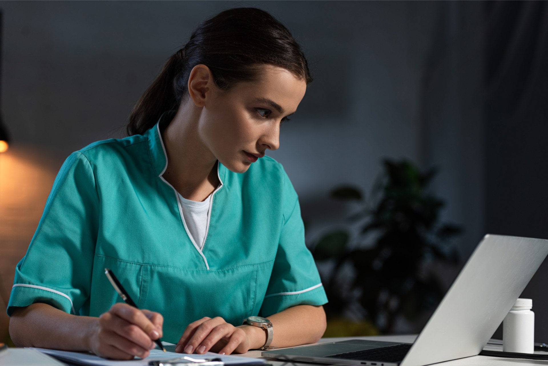 Nurse looking at her laptop writing notes
